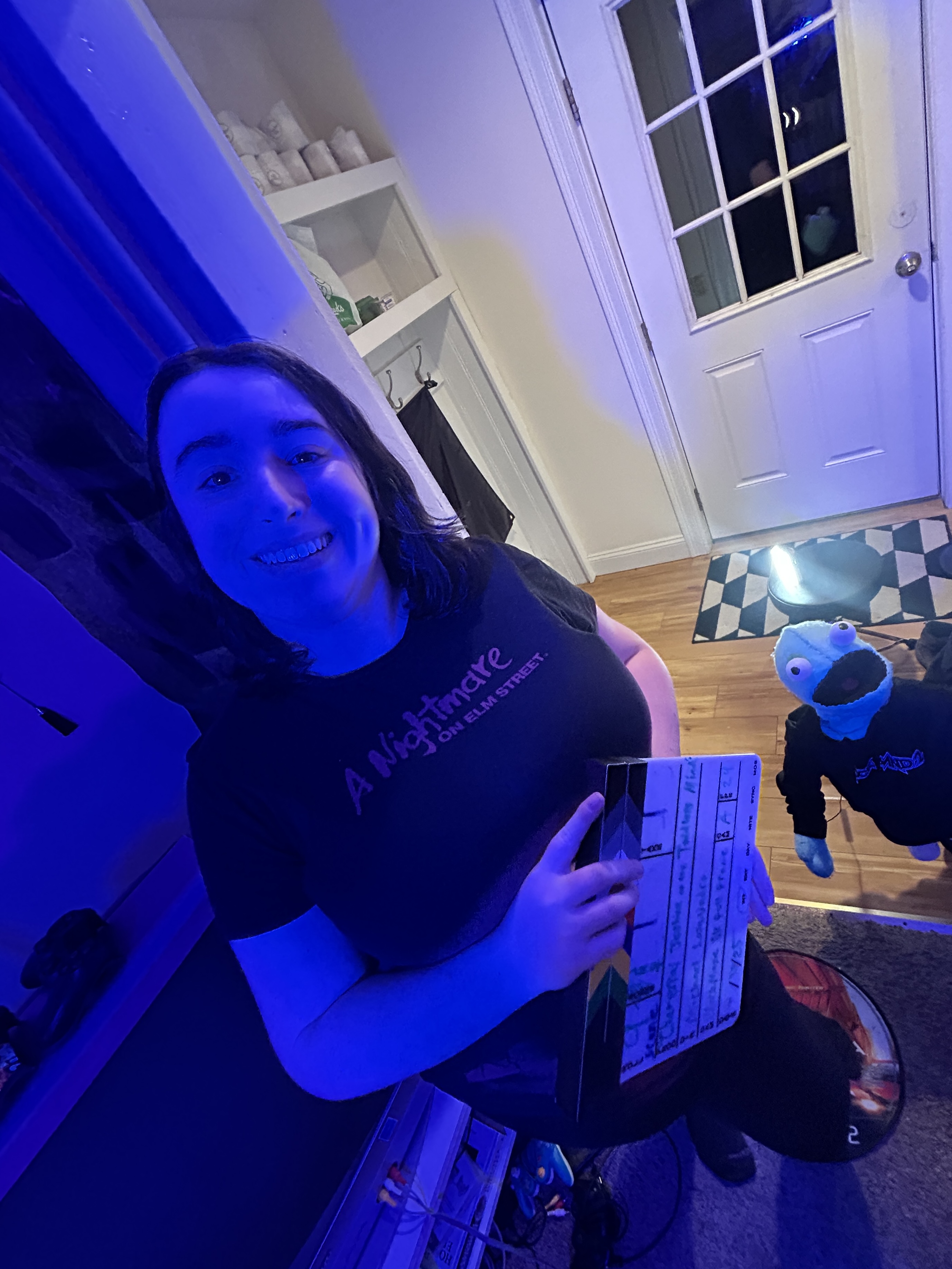 Krystal McAdams posing with Chet, they are smiling, holding a slate while Chet is grinning at knee height.